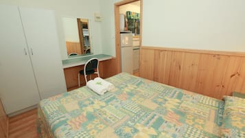 Un dormitorio con cama, escritorio, silla y armario.