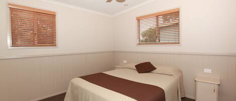 A bedroom with a bed, a nightstand, a ceiling fan, and two windows with blinds.