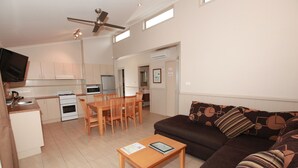 Una cocina moderna con comedor, una sala de estar con sofá y cojines, y un ventilador de techo.