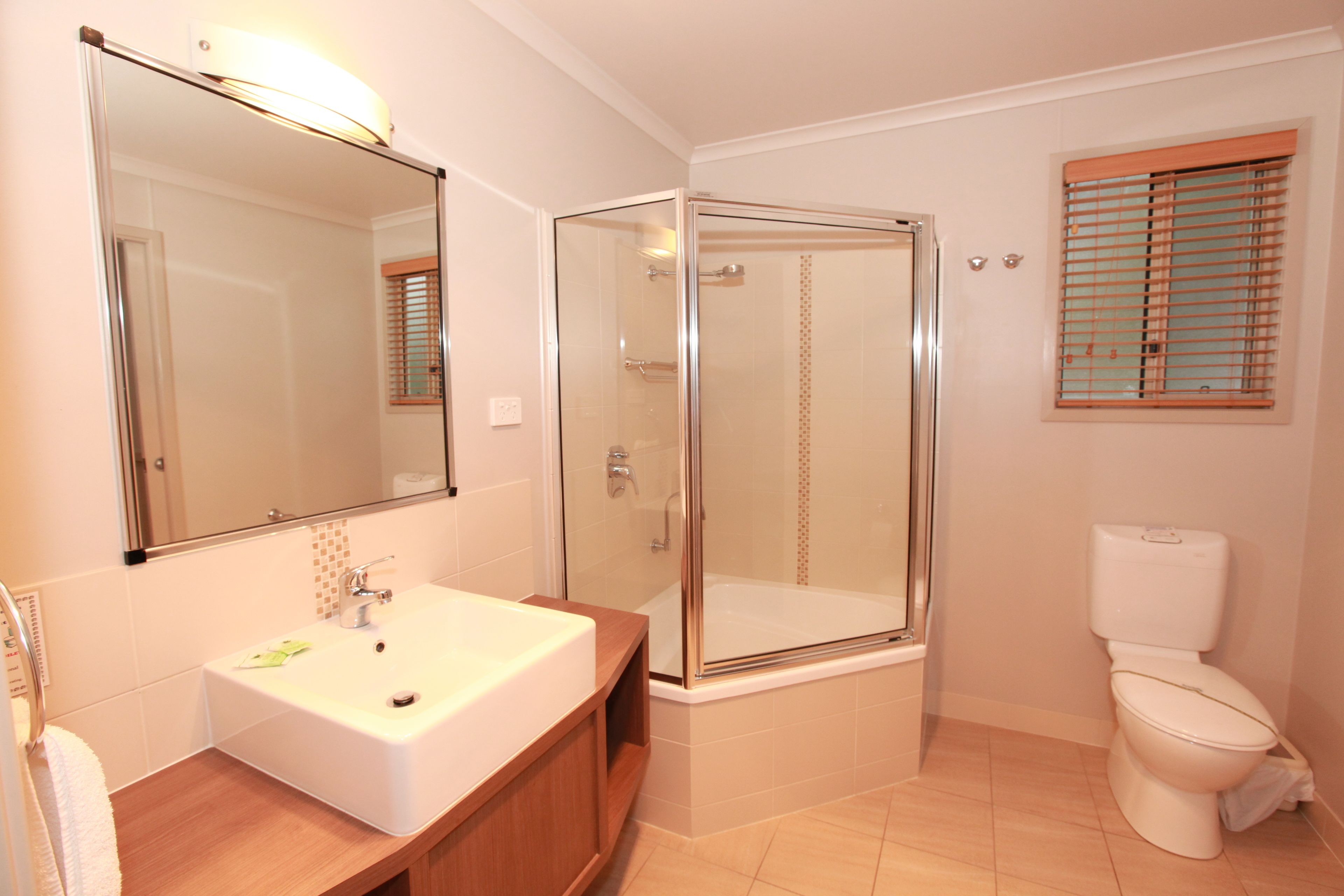 Un baño con cabina de ducha de vidrio, un lavabo blanco y un inodoro.