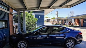 A blue car parked in a parking lot with a building in the background. - Moura Meridian Motel (Moura)