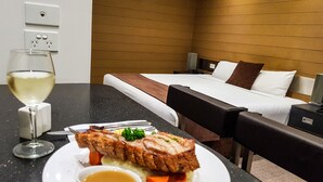 A hotel room with a bed, bedside tables, a dining table with a meal, and a wine glass. - Moura Meridian Motel (Moura)
