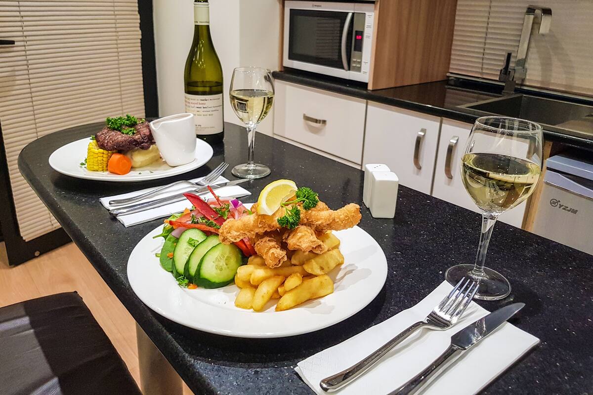 A dining table with plates of food, glasses of wine, and cutlery.