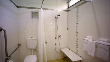 A small, modern bathroom with a shower, toilet, and a bench.
