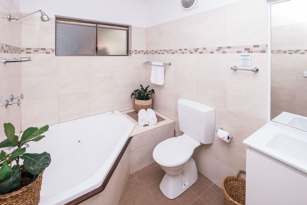 Ein Badezimmer mit Badewanne, Toilette und einem kleinen Topfpflanzen.