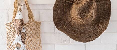 Un muro de ladrillo blanco con un sombrero tejido y un bolso decorativo colgados.