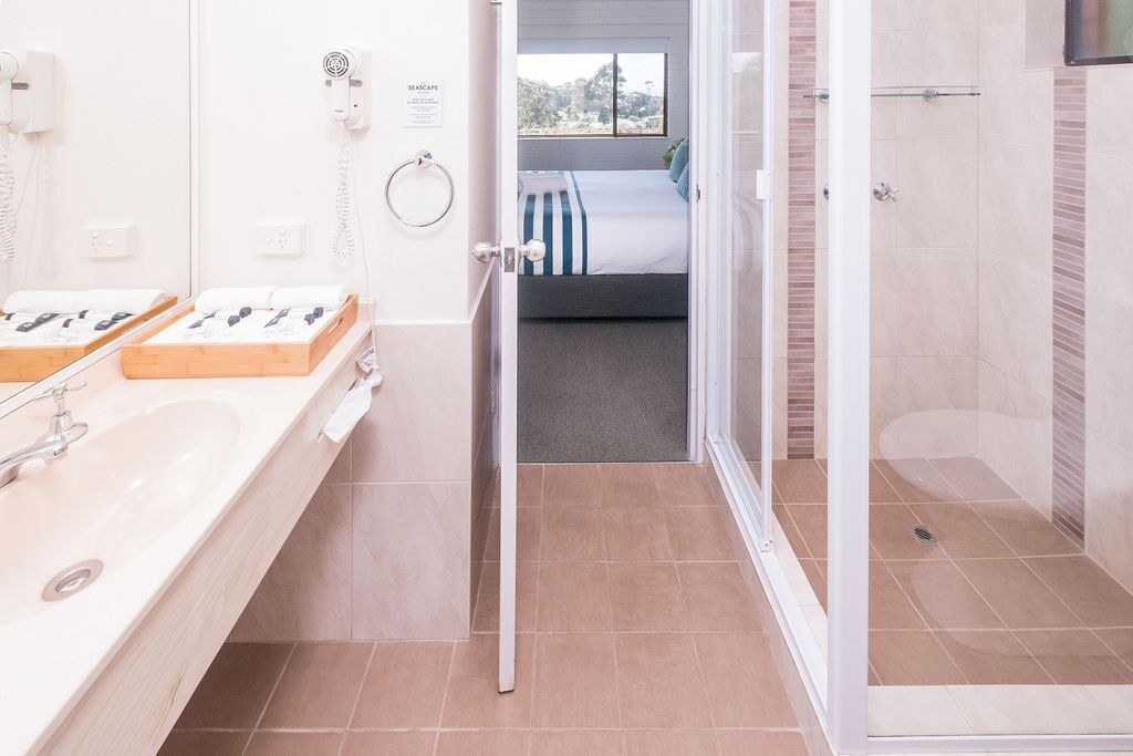 Ein Hotelbad mit einem großen Waschbecken, einem Spiegel und einer Duschkabine.