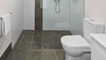 Baño con ducha, inodoro y toallero.