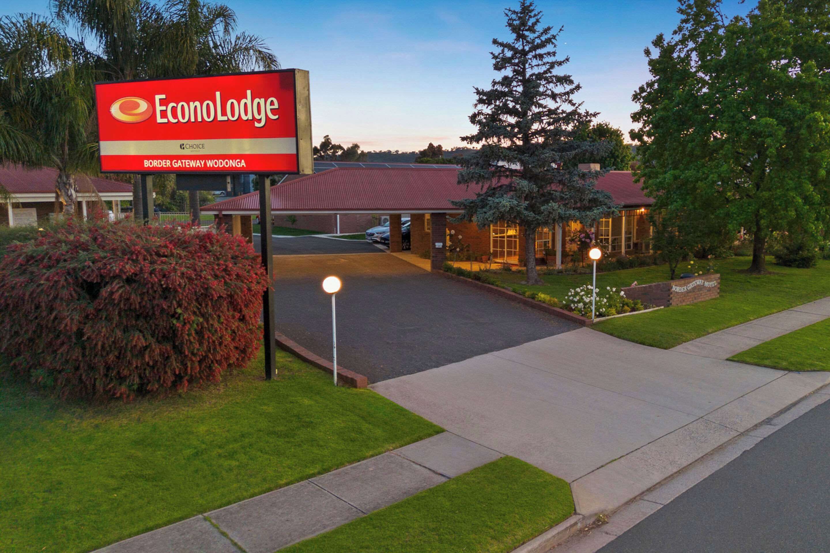 An EconoLodge sign, a parking lot, and a building with a red roof.