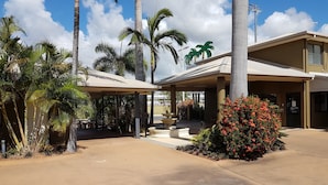 A hotel with a covered outdoor area, palm trees, and a fountain. - Rockhampton Palms Motor Inn (Rockhampton)