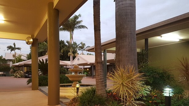 A well-lit outdoor area with a fountain, palm trees, and a covered walkway. - Rockhampton Palms Motor Inn (Rockhampton)