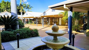 A courtyard with a central fountain, surrounded by palm trees and a covered seating area. - Rockhampton Palms Motor Inn (Rockhampton)