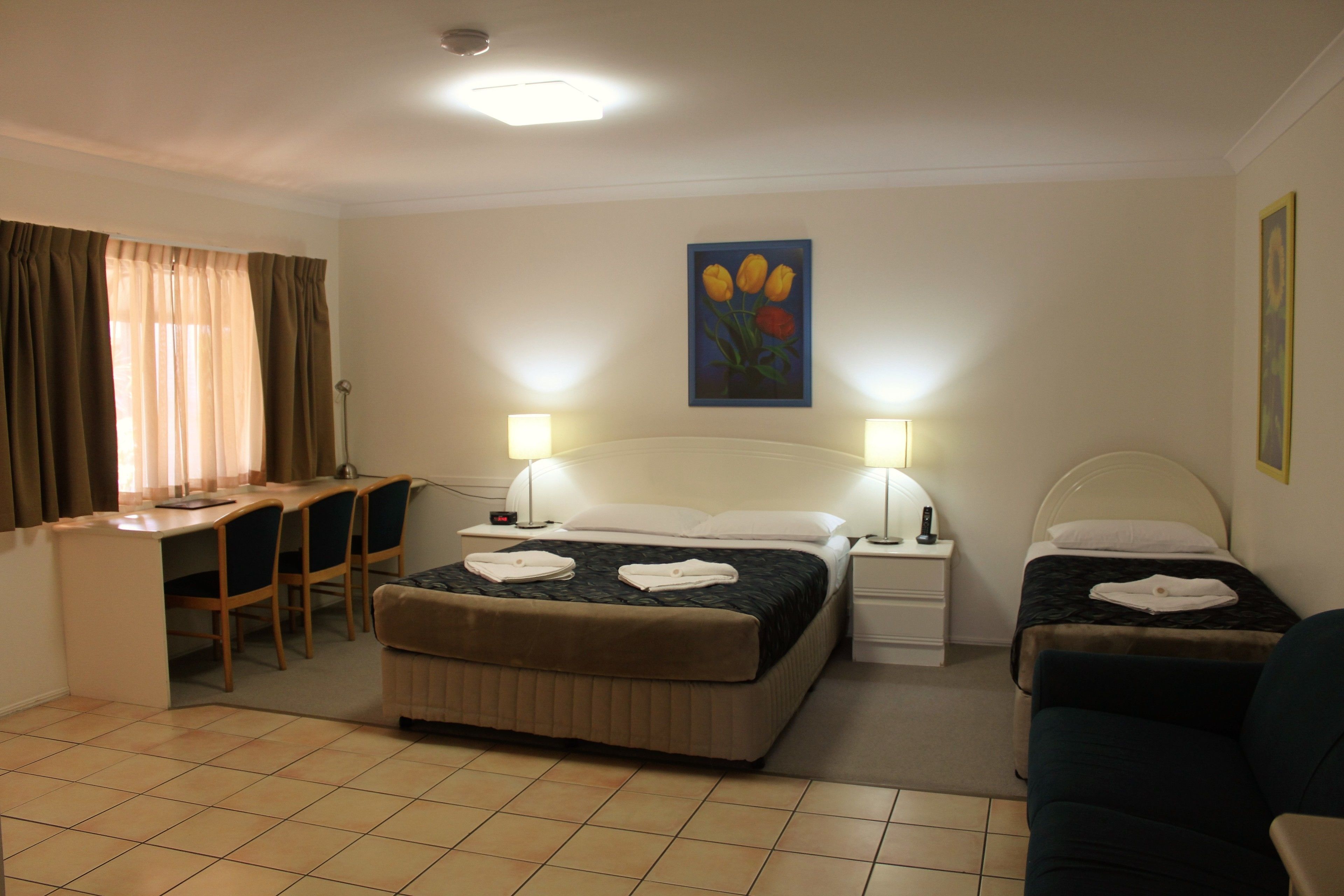A hotel room with a bed, two bedside tables, a desk with chairs, and a couch.