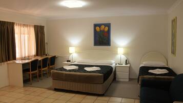 A hotel room with a bed, two bedside tables, a desk with chairs, and a couch.
