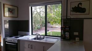 A kitchen with a large window, a stove, and a sink. - Amy's House (Auburn)