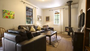 A living room with a sofa, a coffee table, a TV, and a fireplace. - Amy's House (Auburn)