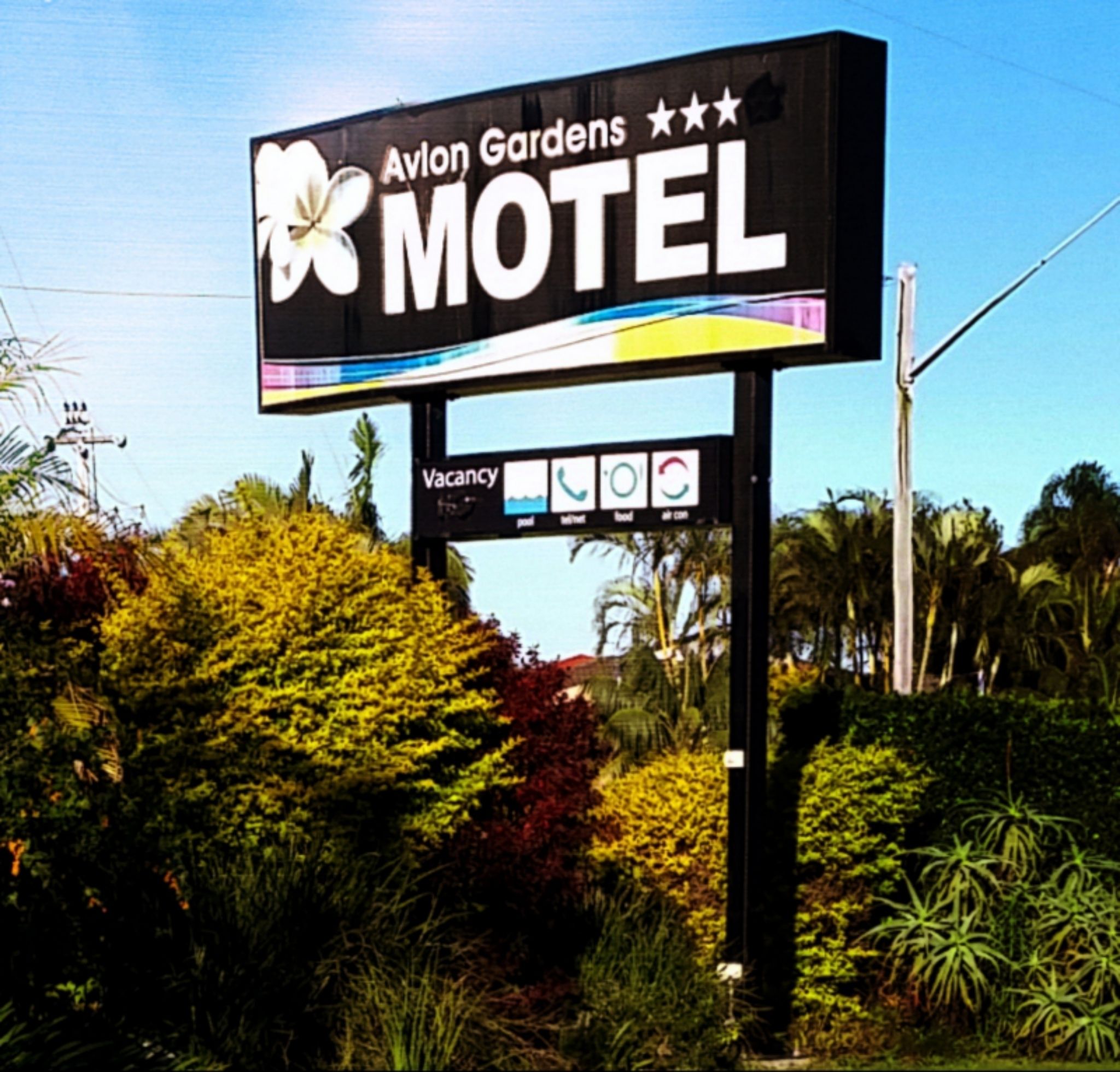 A motel sign with a flower logo and the name 'Avlon Gardens Motel'.