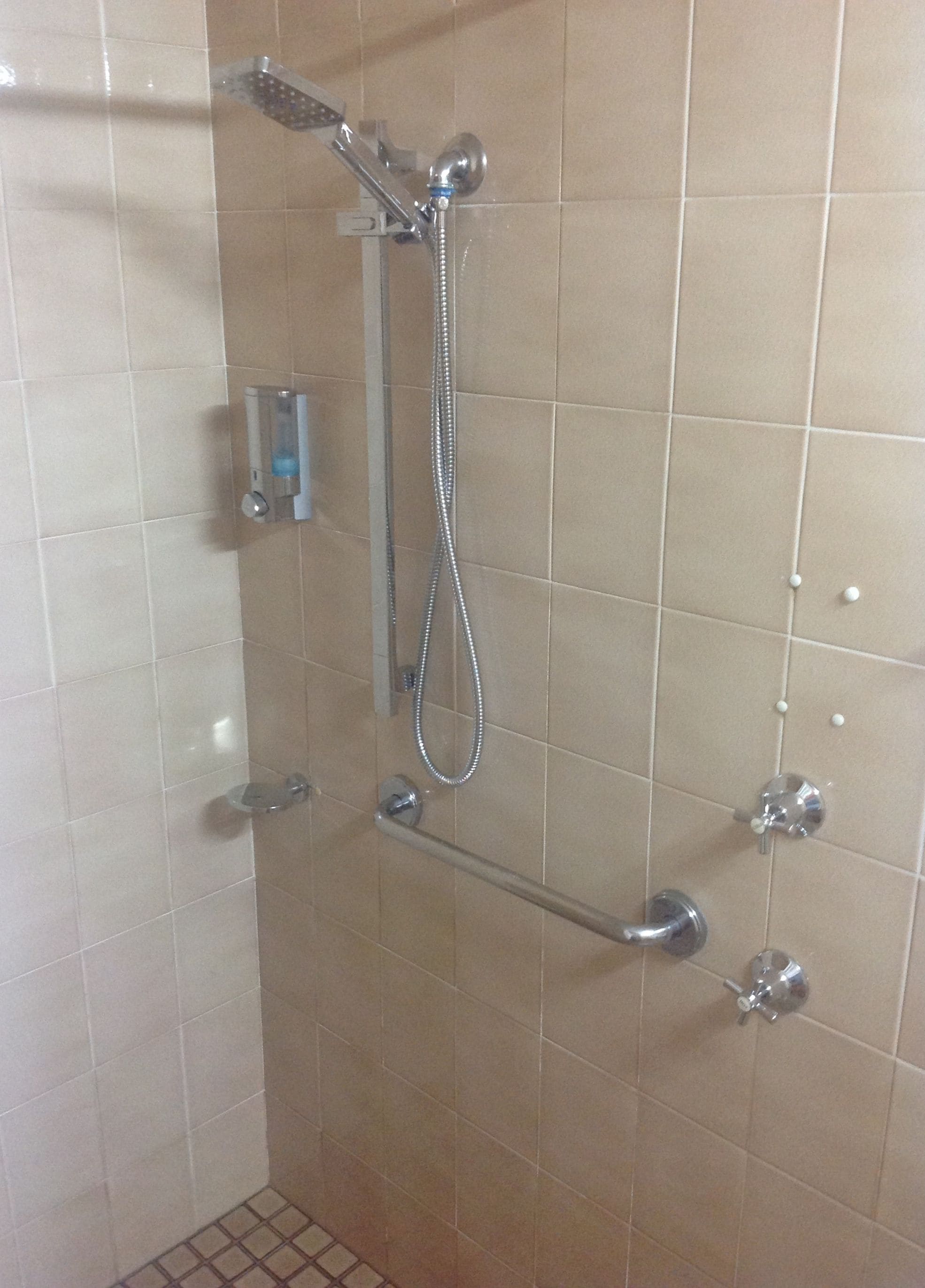 A shower with a handheld showerhead, a handheld shower attachment, and a handheld shower hose.