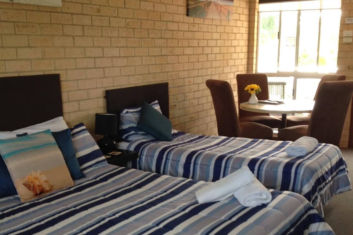 Een hotelkamer met twee bedden, een kleine tafel en een stoel.