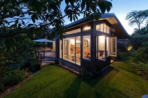 A modern house with large glass windows, a well-maintained lawn, and a patio area. - Stone Store Lodge (Kerikeri)