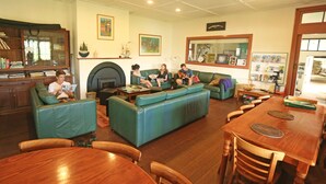 Una sala de estar acogedora con chimenea, sofás de cuero verde, una mesa de comedor de madera y una estantería.