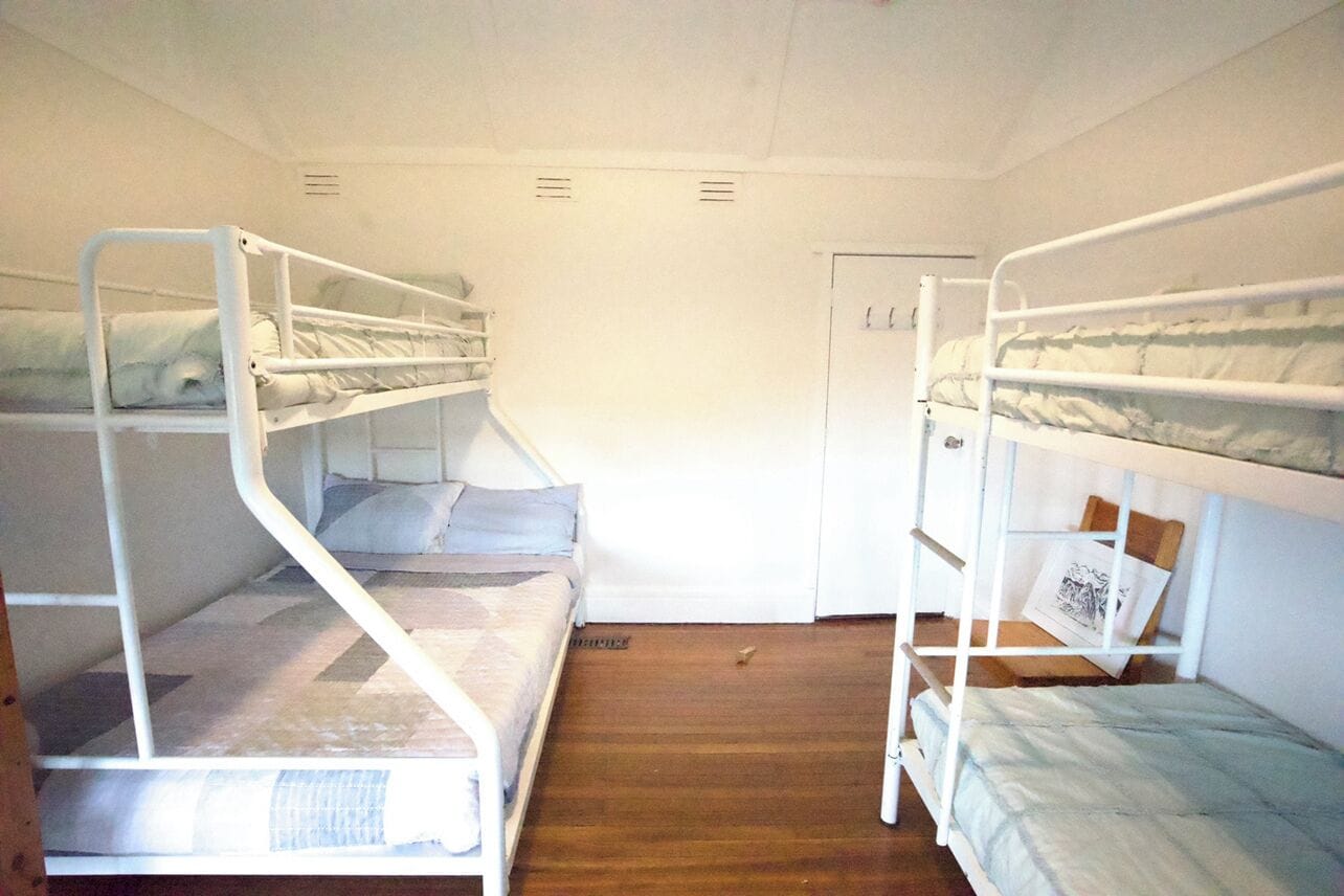 Ein Zimmer mit Etagenbetten, Holzboden und einer weißen Tür.