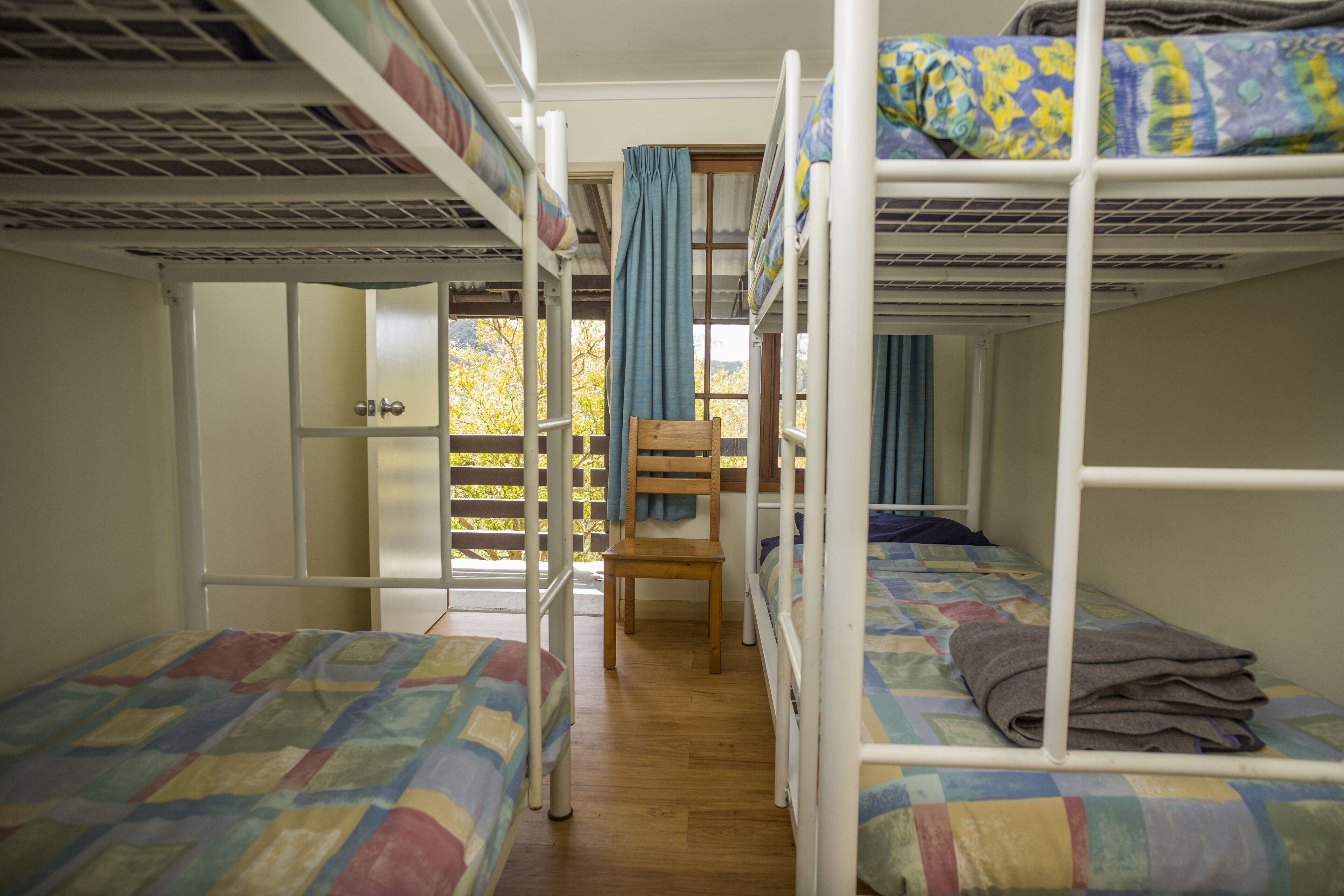 Ein Schlafsaalzimmer mit Etagenbetten, einem Holzbett und einem Fenster mit Vorhängen.