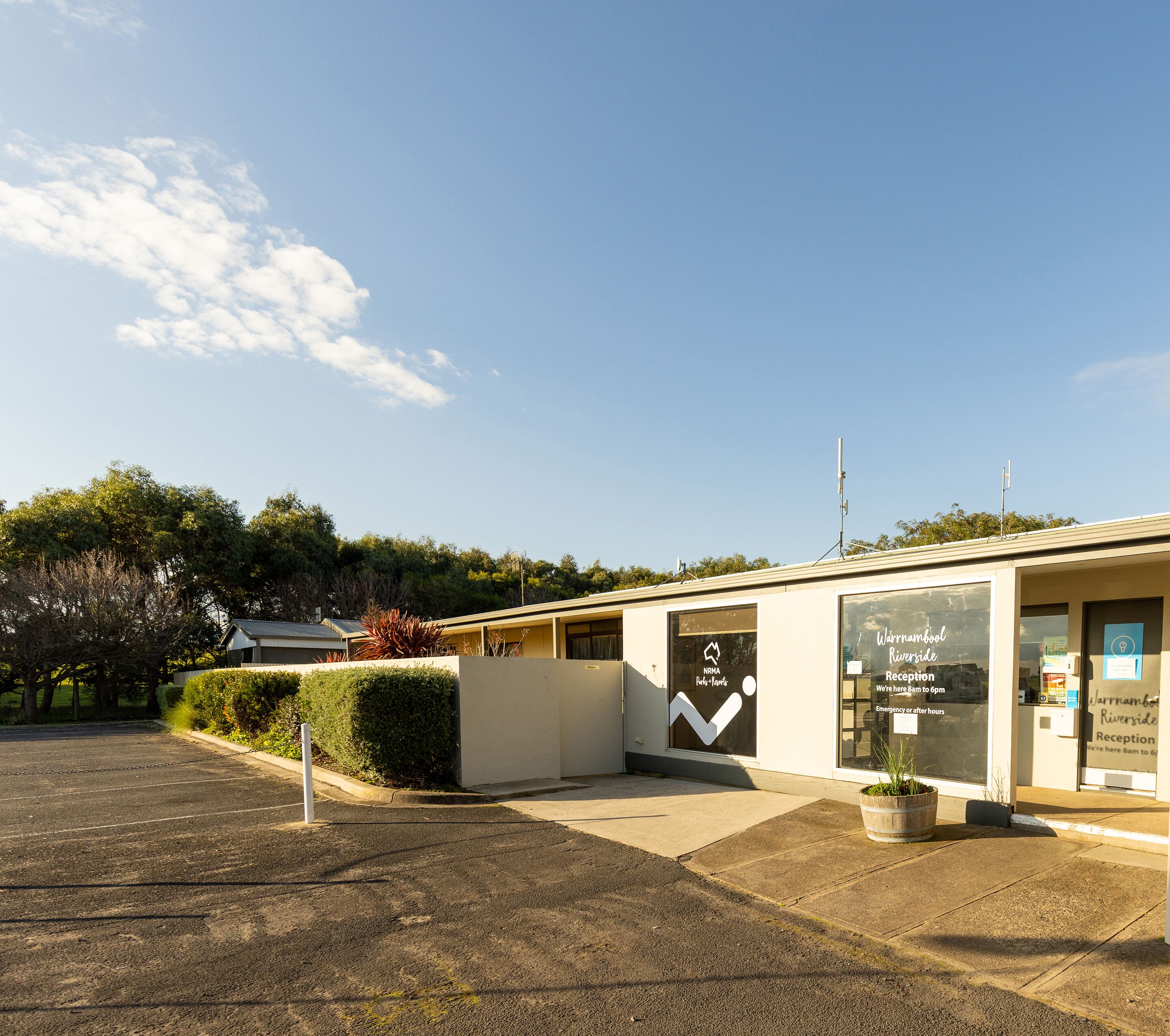 A reception area with a clear sky, a parking lot, and a building with a sign indicating 'Warrnambool Riverside Reception'.