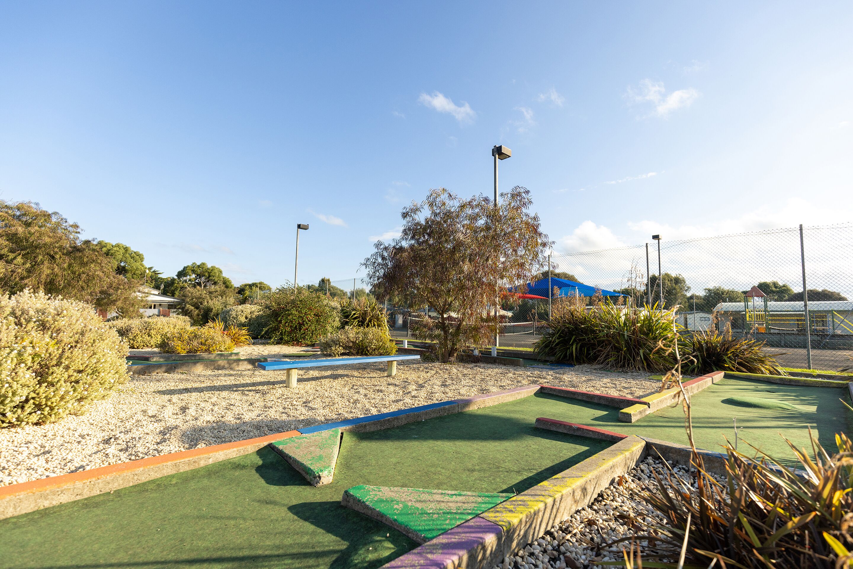 A miniature golf course with a clear path, sand traps, and a blue bench.