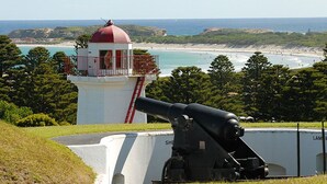 A lighthouse with a red dome, a large cannon, and a scenic view of the beach and ocean. - NRMA Warrnambool Riverside Holiday Park (Allansford)
