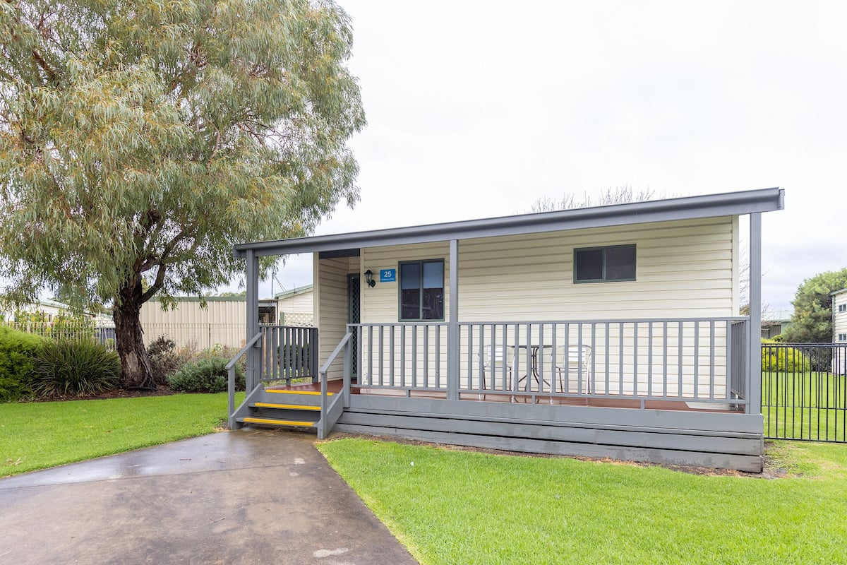 A single-story mobile home with a covered porch and a small set of stairs leading to the entrance.