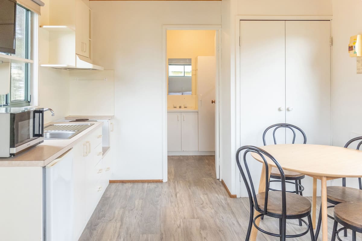 A modern kitchen with white cabinets, a wooden ceiling, and a dining area with a round table and chairs.