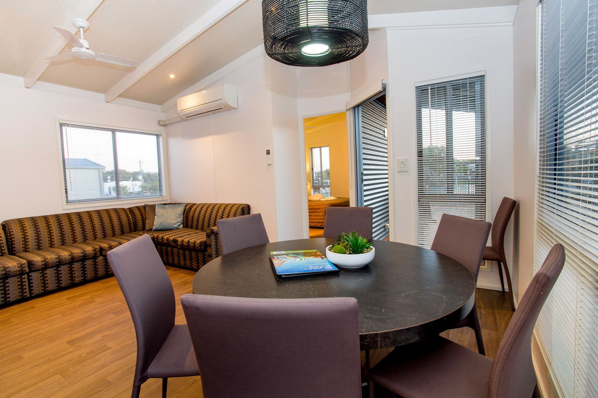 A modern living room with a round table, comfortable seating, and a ceiling fan.