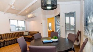 A modern living room with a round table, comfortable seating, and a ceiling fan. - NRMA Warrnambool Riverside Holiday Park (Allansford)