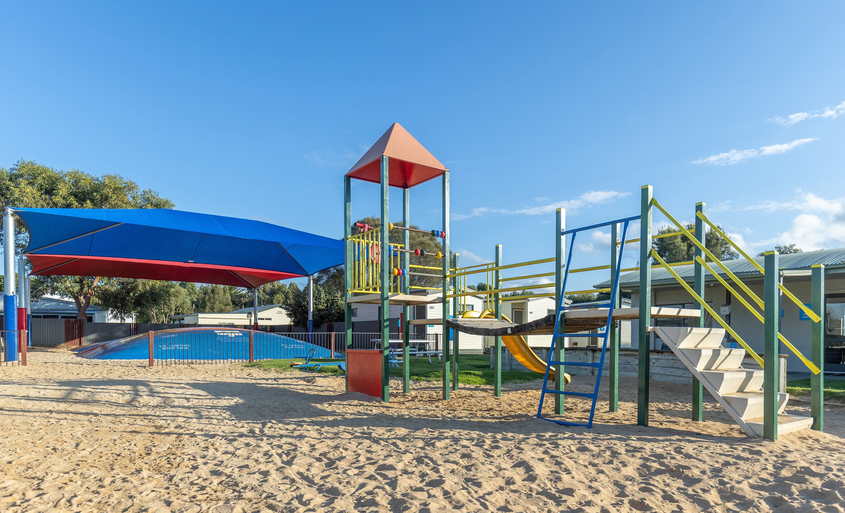 A playground with a climbing structure, slides, and a shaded area.