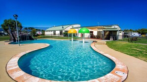 A swimming pool with a curved edge, surrounded by a concrete deck. - NRMA Warrnambool Riverside Holiday Park (Allansford)