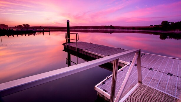 A pier extending into calm water with a sunset in the background. - NRMA Warrnambool Riverside Holiday Park (Allansford)