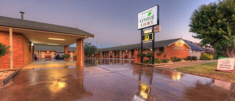 A motel with a covered parking area, a sign indicating vacancy, and a sign for new rooms and great rates.