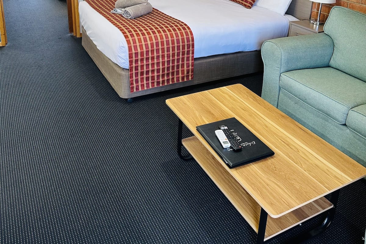A hotel room with a large bed, a sofa, a small table, and a picture on the wall.