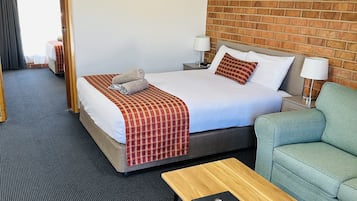 A hotel room with a large bed, a sofa, a small table, and a picture on the wall.