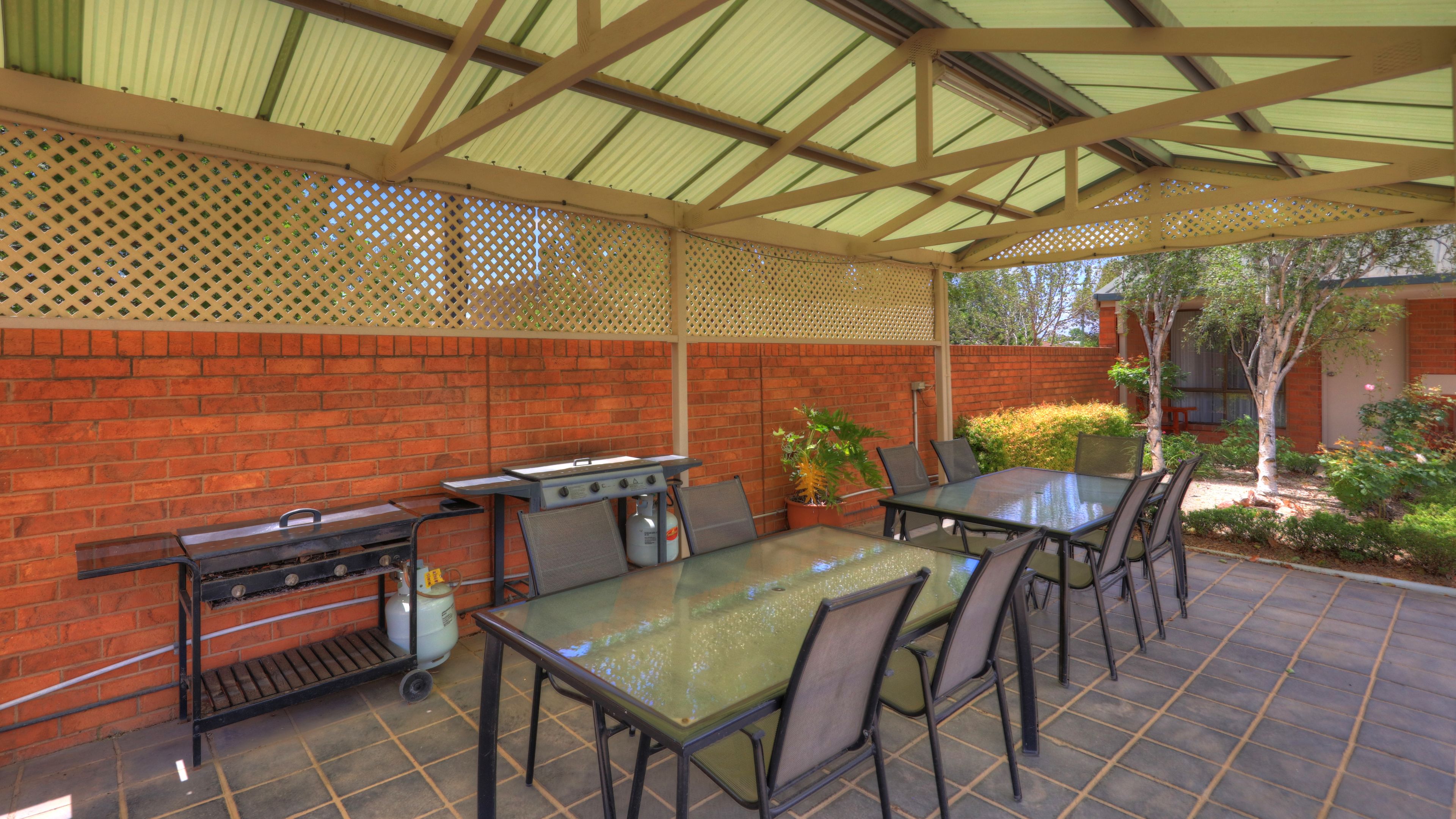 Un patio exterior con una parrilla, una mesa y sillas.