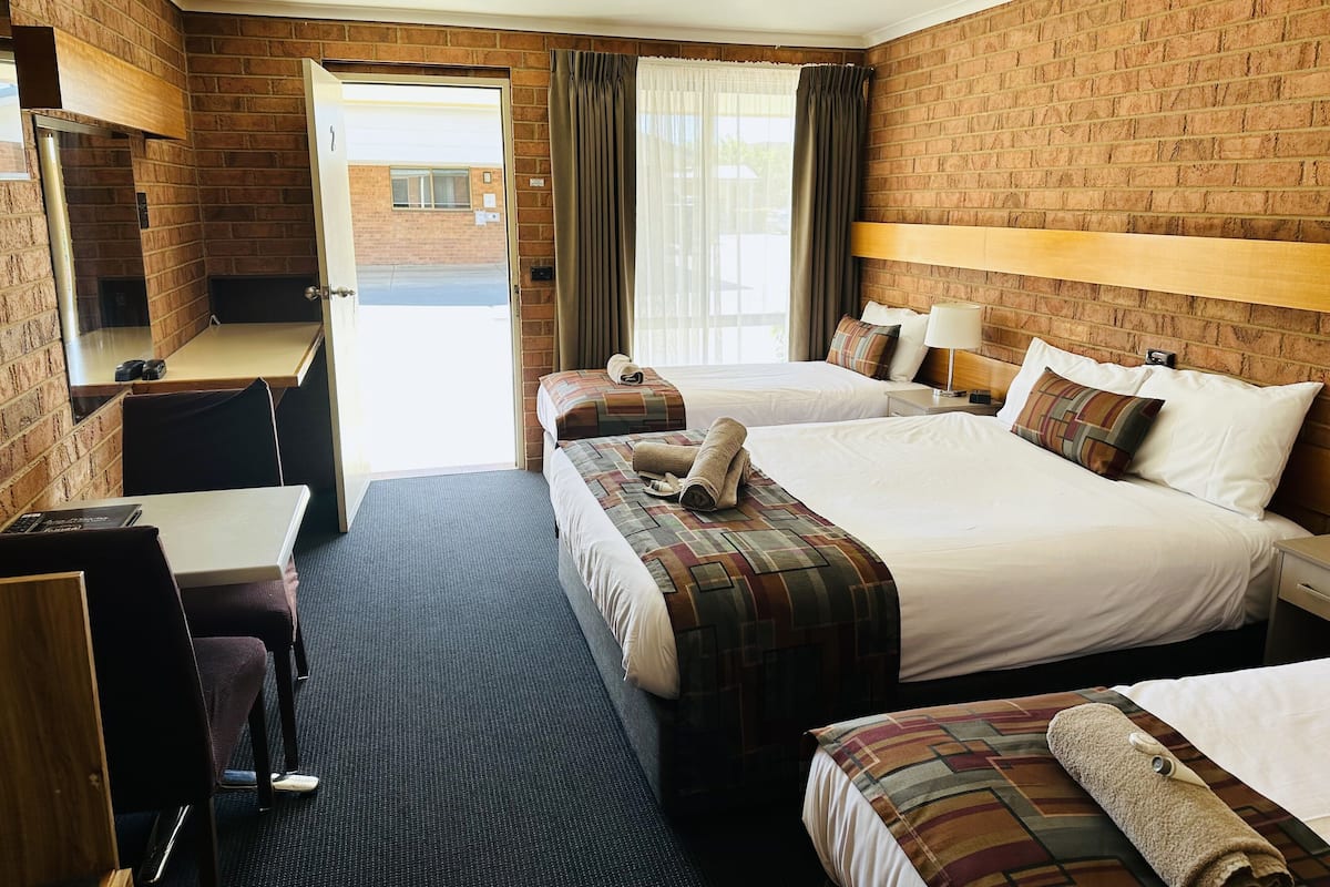 A hotel room with two beds, a desk, a chair, and a TV.