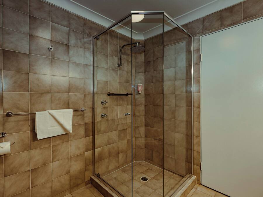 A glass-enclosed shower with a tiled wall, a towel rack, and a door.