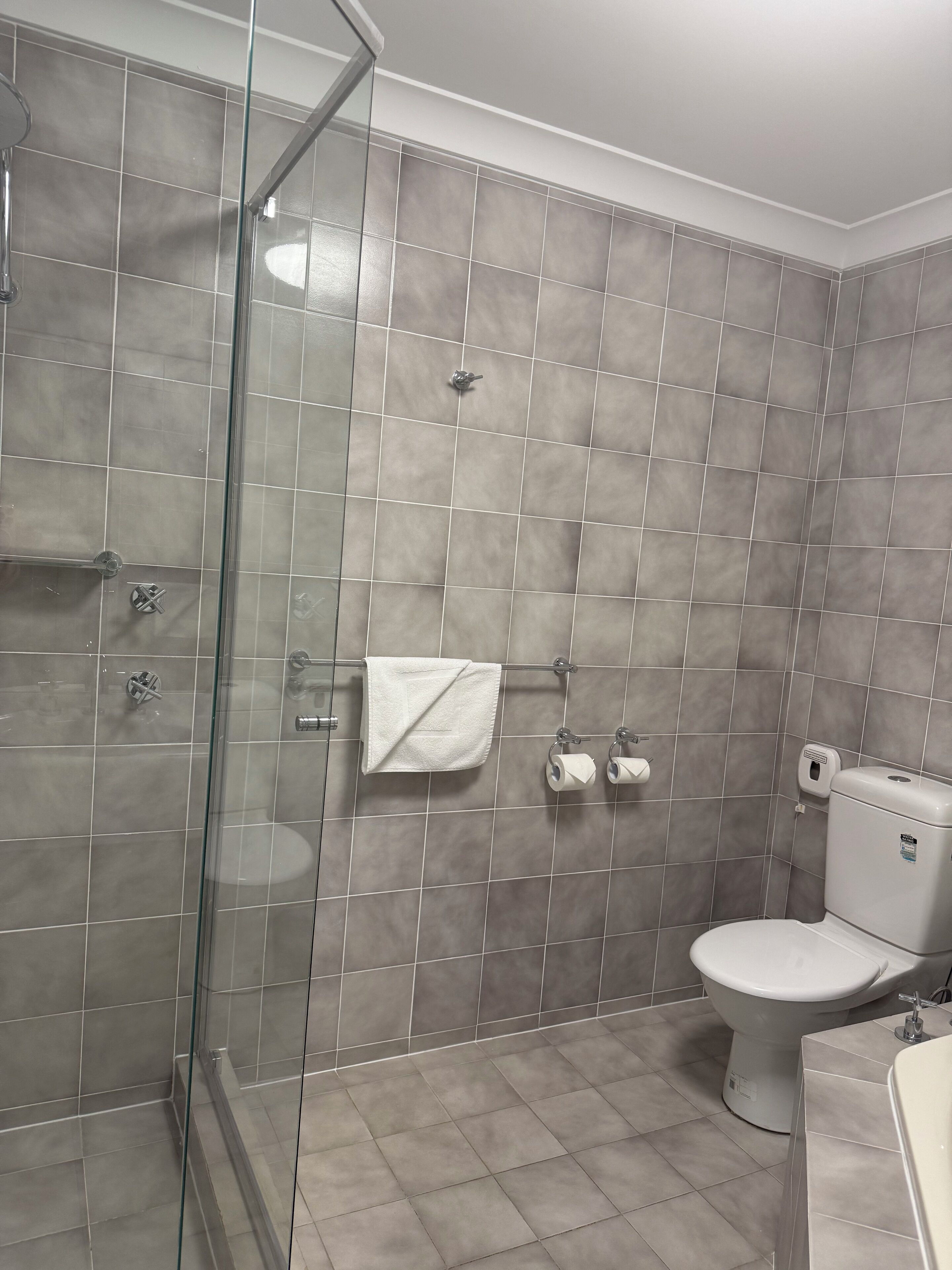 Un bany amb una cabina de dutxa de vidre, un vàter i un lavabo.