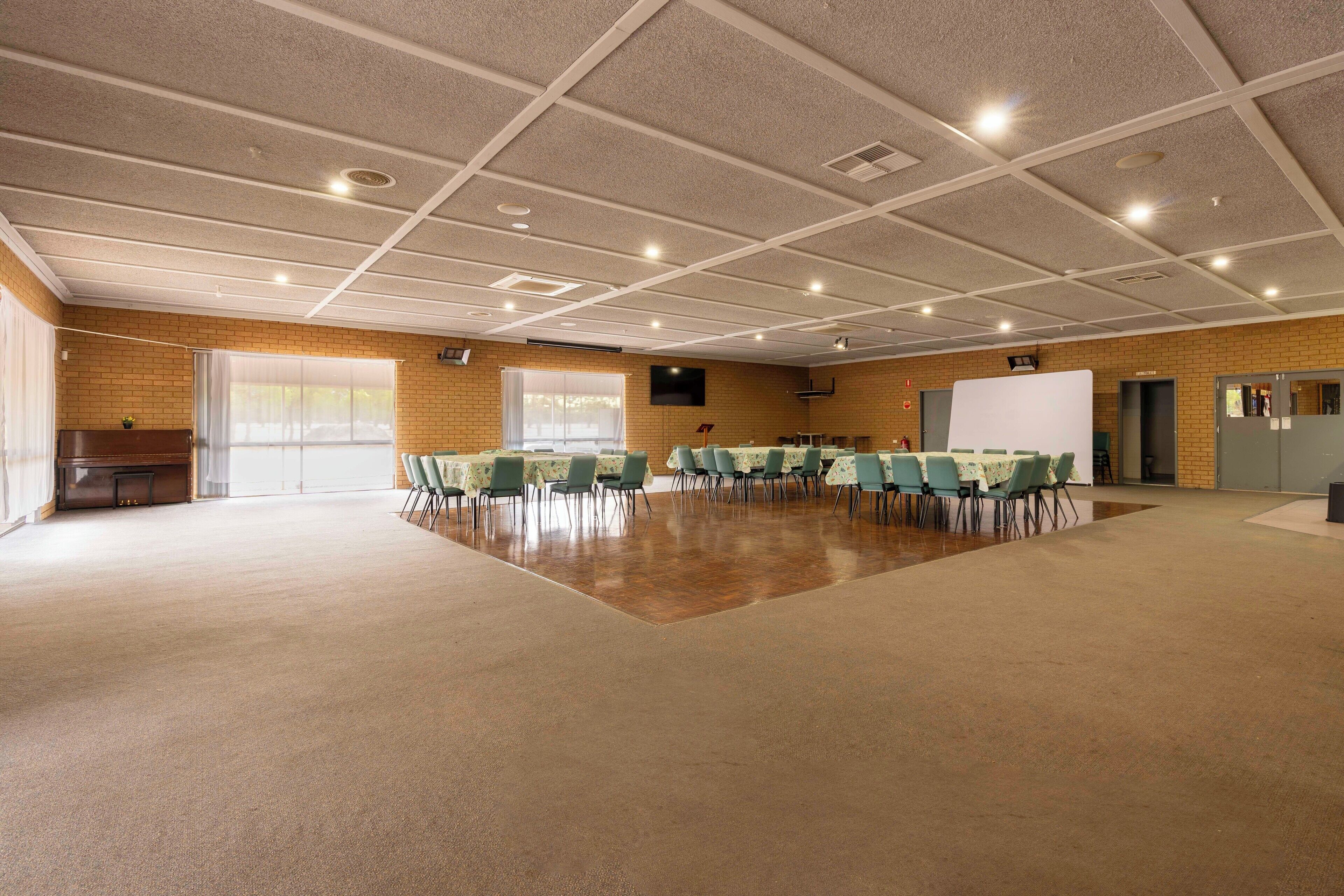 Una amplia sala de conferencias con techo alto, ventanas grandes y una pizarra.