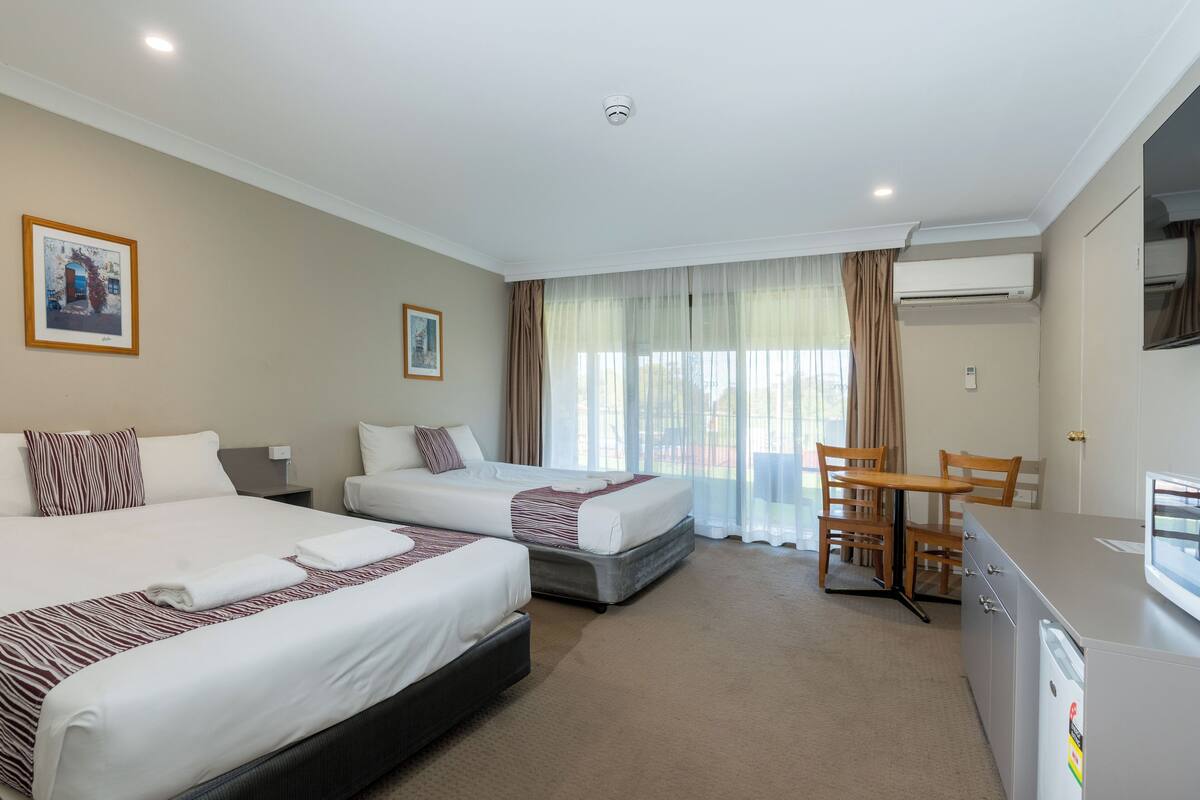 A hotel room with two beds, a dining table, and a kitchenette.