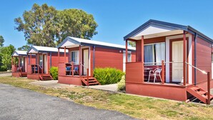Filas de casas móviles rojas con porches individuales, cada uno con una pequeña mesa y sillas.