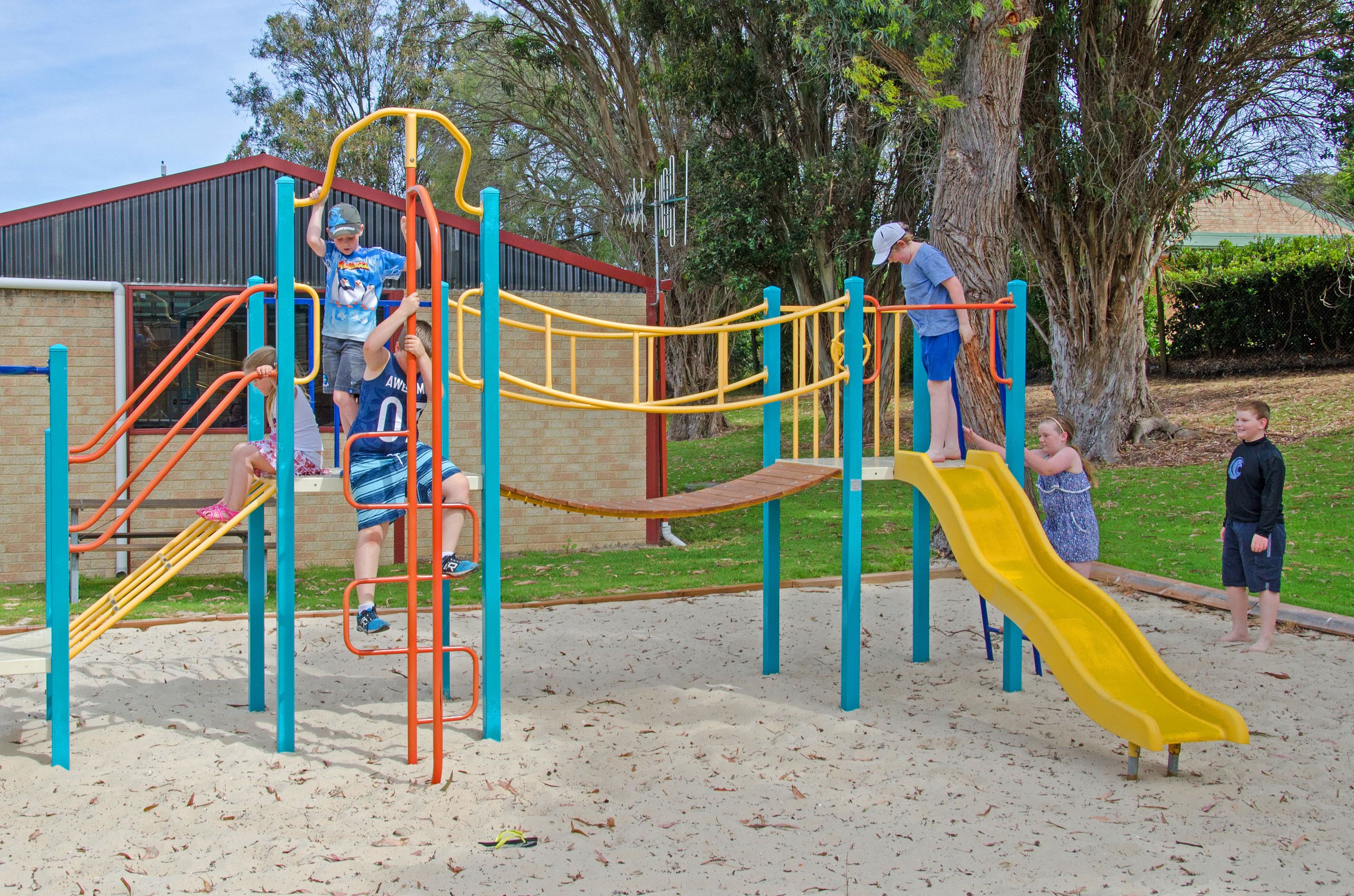Un parque infantil con estructuras para escalar, un tobogán y arena.