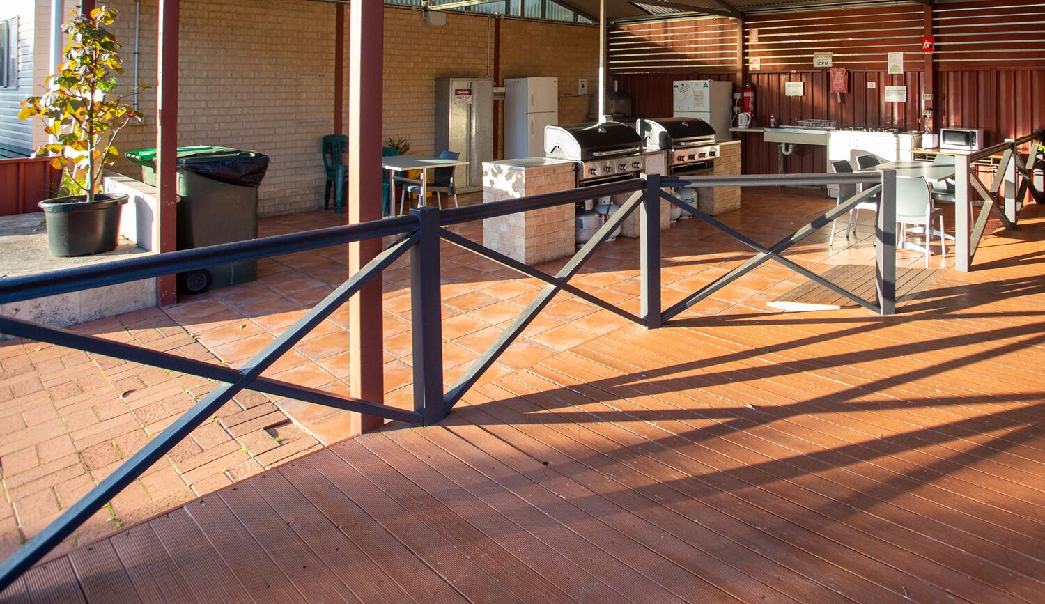 Un patio al aire libre con una parrilla, asientos y un contenedor de basura.