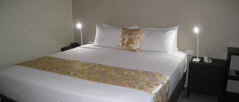 A neatly made bed with a floral bedspread, two bedside lamps, and a framed picture on the wall.